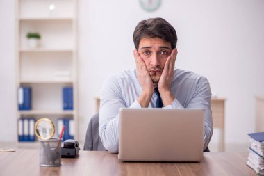 Genç erkek çalışan işyerinde oturuyor.