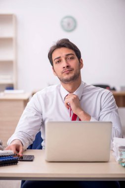 Genç erkek çalışan işyerinde oturuyor.