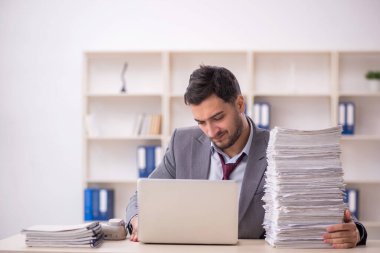 Young employee and too much work at workplace