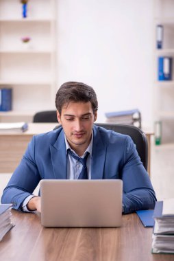 Genç bir erkek işçi ve işyerinde çok fazla iş var.