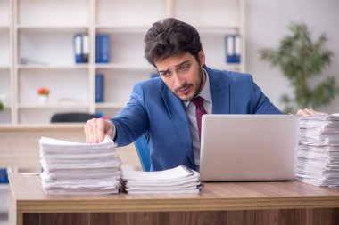 Young employee and too much work at workplace