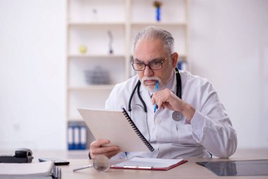 Klinikte çalışan yaşlı bir doktor.