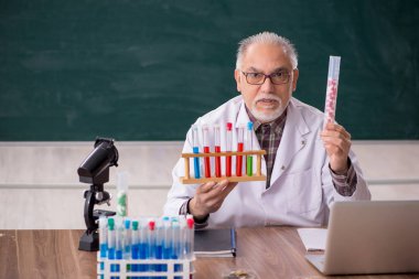 Old teacher chemist sitting in the classroom