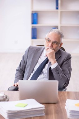 Old businessman employee unhappy with excessive work at workplace