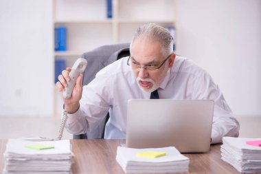 Old businessman employee unhappy with excessive work at workplace