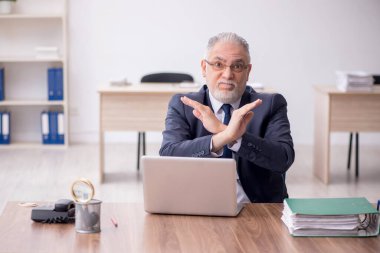 Old employee sitting at workplace