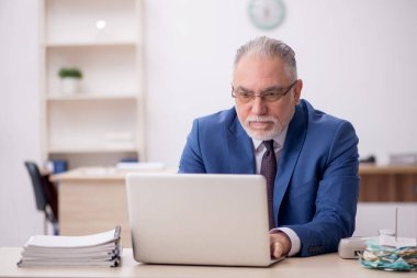 Old employee sitting at workplace