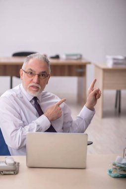 Old employee sitting at workplace