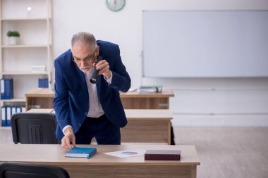 Old teacher holding penlight in the classroom