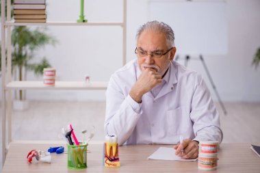 Klinikte çalışan yaşlı bir dişçi.