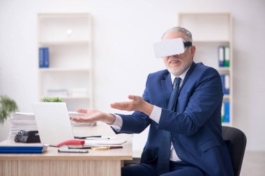 Old businessman employee wearing virtual glasses in the office