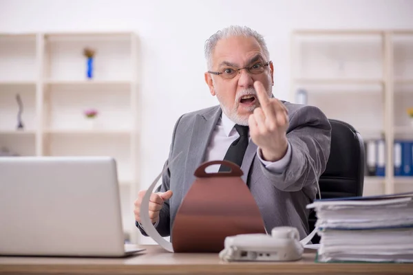 Old businessman employee eating cake at workplace