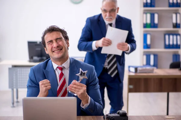 Two male employees with star award in the office