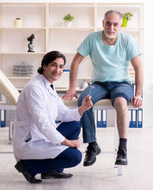 Yaşlı adam genç erkek doktoru ziyaret ediyor.