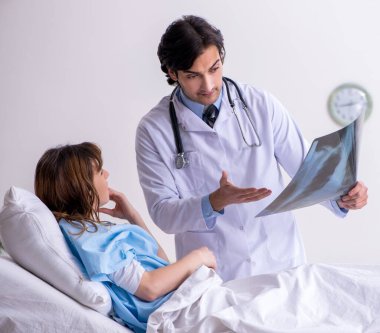 Erkek doktor koğuştaki kadın hastayı ziyaret ediyor.