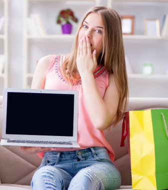 Alışveriş poşetleriyle evde, kanepede oturan genç kadın.