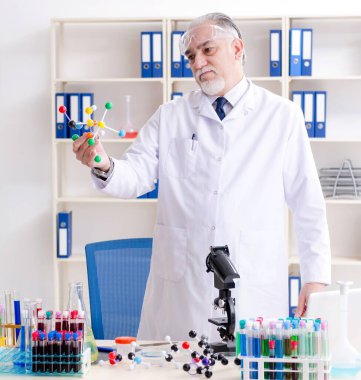 Laboratuvarda çalışan yaşlı erkek kimyager.