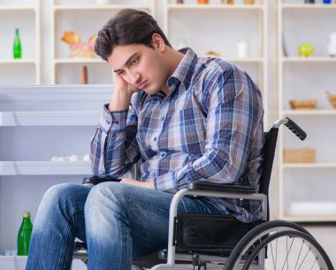 Genç sakat adam buzdolabının kapısını açıyor.