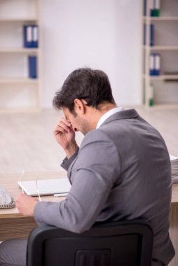 Genç işadamı işyerinde oturuyor.