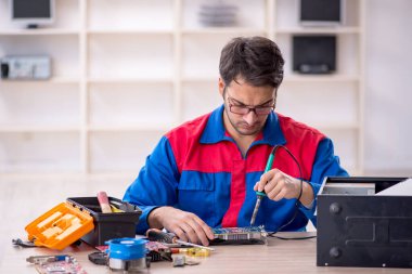 Atölyede bilgisayar tamir eden genç bir tamirci.