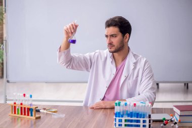 Young chemistry teacher sitting in the classroom