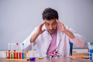 Young chemistry teacher sitting in the classroom