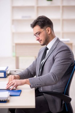 Genç işadamı işyerinde oturuyor.
