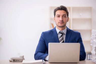 Young employee and too much work at workplace