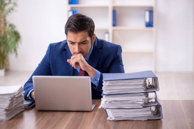 Genç işadamı ve işyerinde çok fazla iş var.