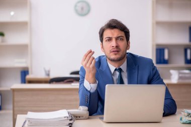 Genç erkek çalışan işyerinde oturuyor.