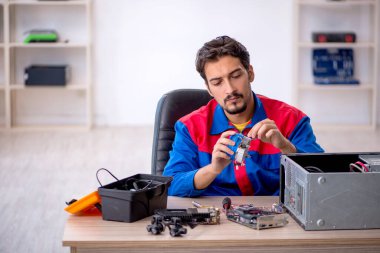 Atölyede bilgisayar tamir eden genç bir tamirci.