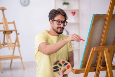 Genç erkek ressam evde resim yapmaktan hoşlanıyor.