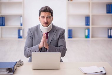 Young employee after car accident sitting at workplace