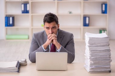 Young employee and too much work at workplace