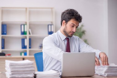 Young employee and too much work at workplace