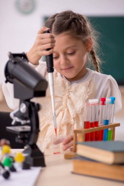 Little girl studying chemistry in the classroom