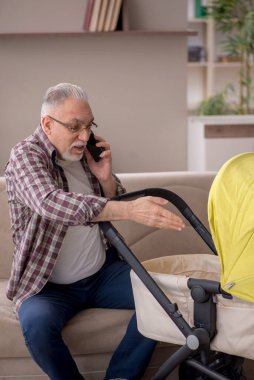 Old man looking after baby at home