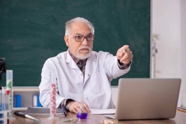 Old teacher chemist sitting in the classroom