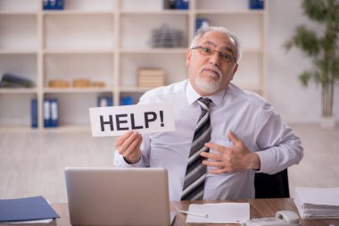 Old businessman employee unhappy with excessive work at workplace