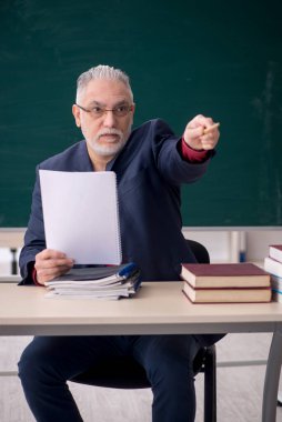 Old teacher sitting in the classroom
