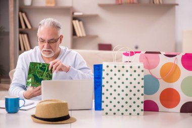 Old man with many bags in Christmas concept indoors