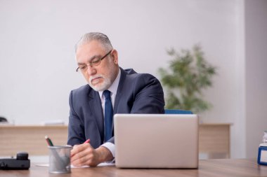 Old employee sitting at workplace