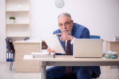 Old employee sitting at workplace