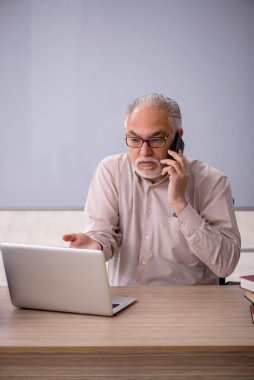 Eski öğretmen beyaz tahtanın önünde.