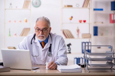 Klinikte çalışan yaşlı bir doktor.