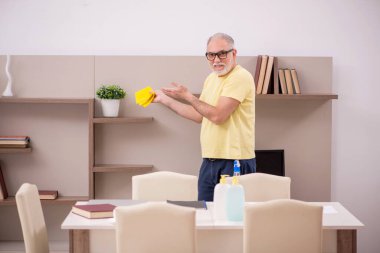 Yaşlı adam evi temizliyor.