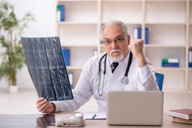 Klinikte çalışan yaşlı erkek radyoloji uzmanı.