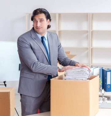 The young man employee with boxes in the office