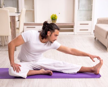 Genç adam evde fiziksel egzersiz yapıyor.