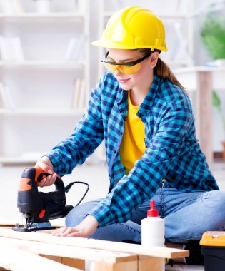 Tamirci kadın marangoz, ahşap döşemeleri onarım için kesiyor.